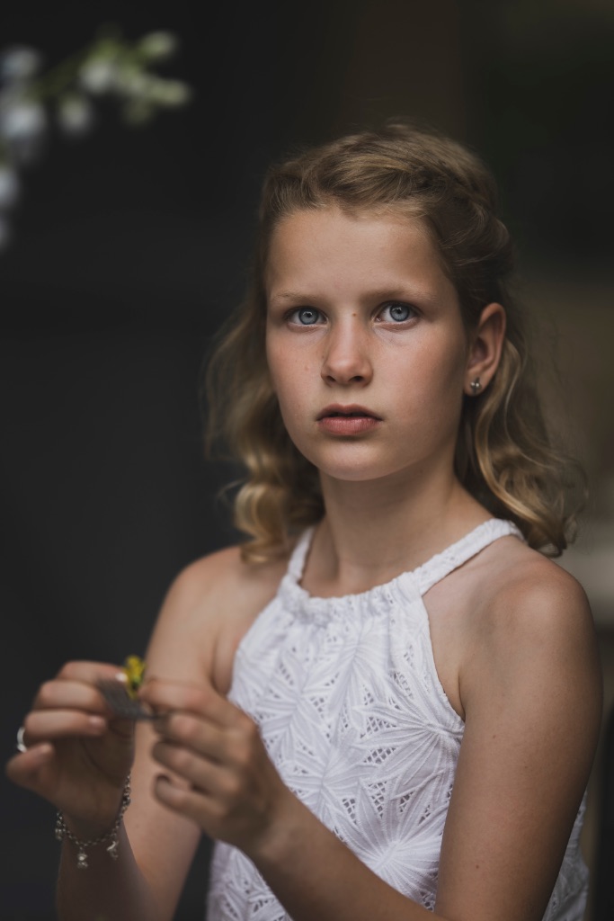 Portret van een bruidsmeisje in een witte jurk met een gele bloem in haar handen, bruiloft Elena en Roeland